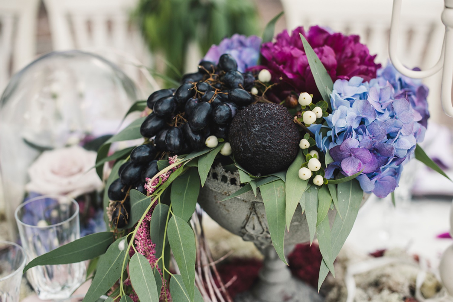 Elegant centerpiece: purple hydrangeas, dark grapes, and an avocado
