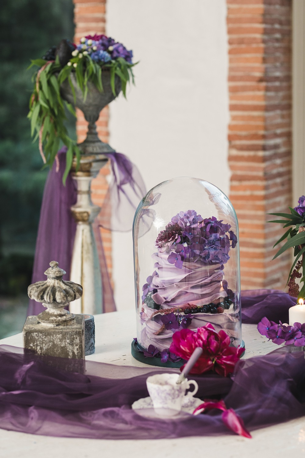 Purple wedding cake under glass dome with flowers