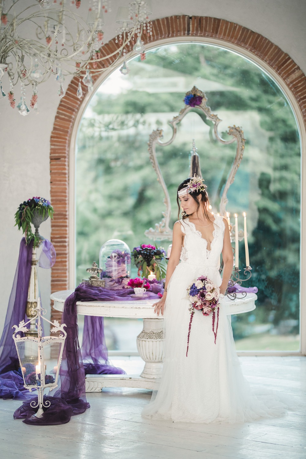 Bride in white gown poses near purple flowers