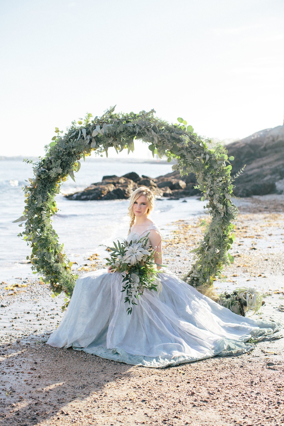 bride on a beach with giant wreath backdrop