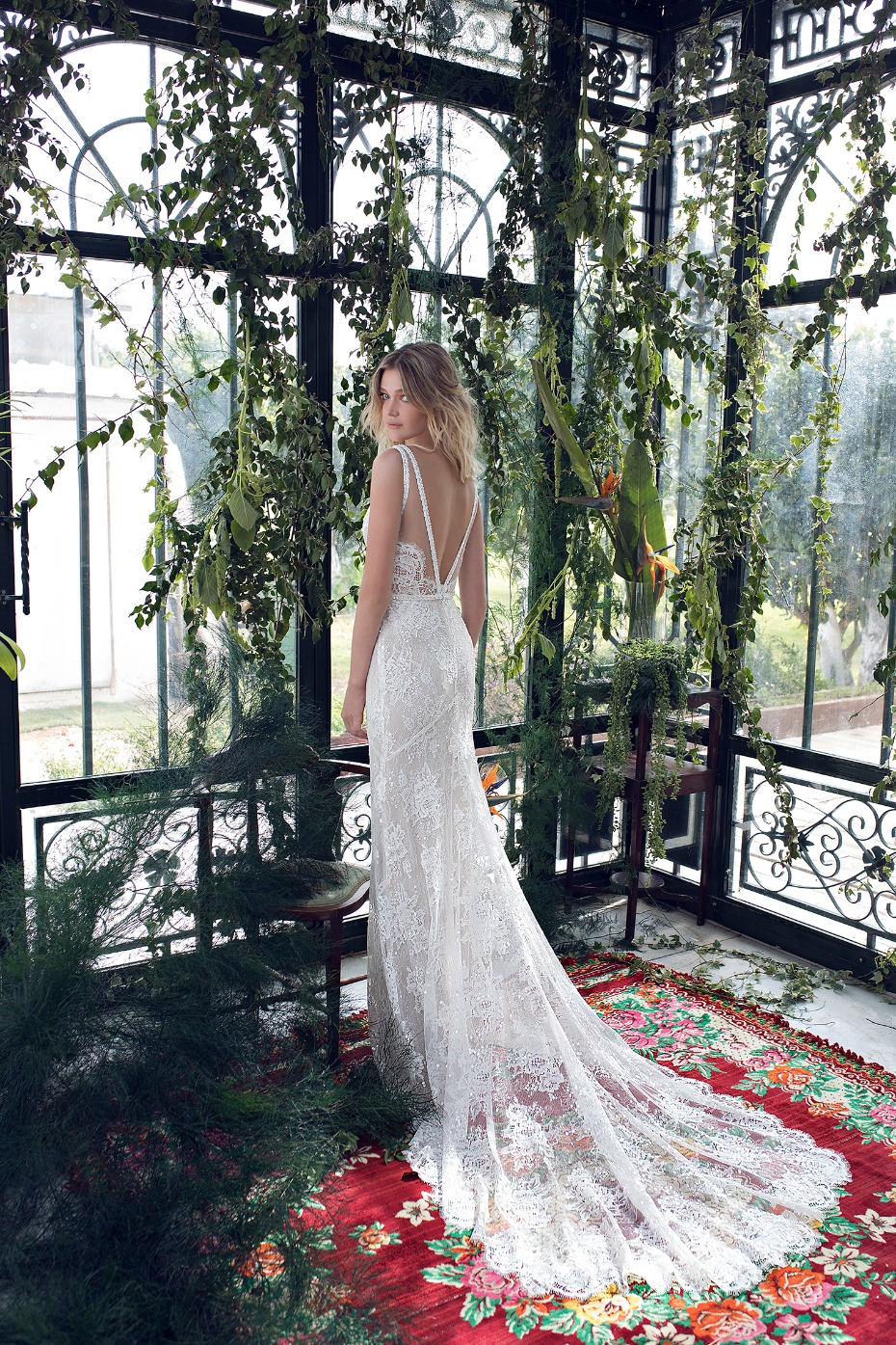 Bride in a lace wedding dress standing in a greenhouse