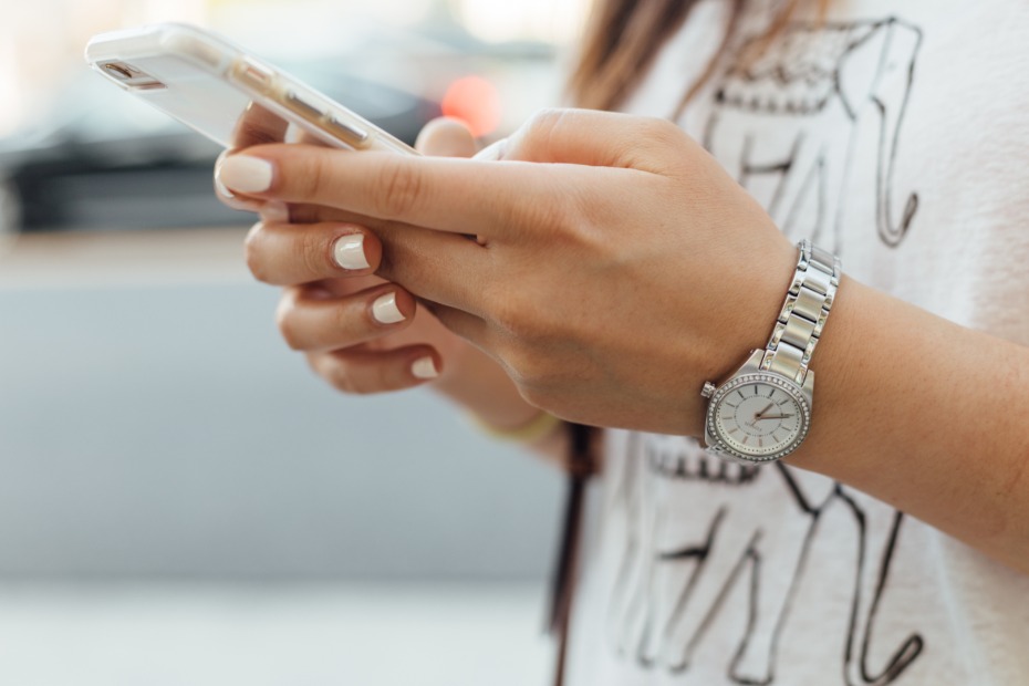 Woman with stylish watch using smartphone in focus