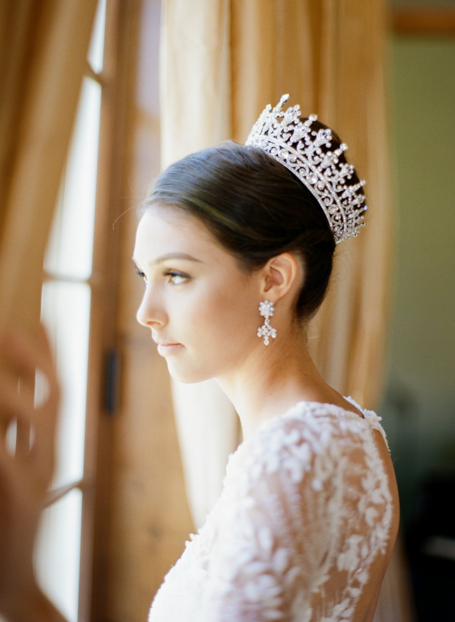 Elegant bride in a crown and earrings near a window