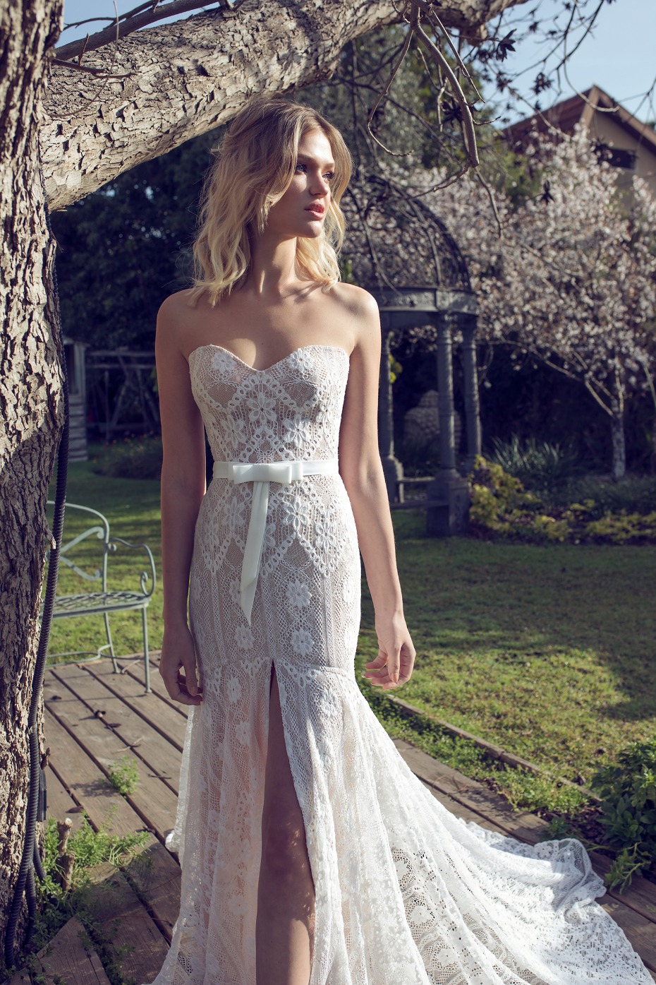 Elegant bride in lace wedding dress with thigh slit in garden