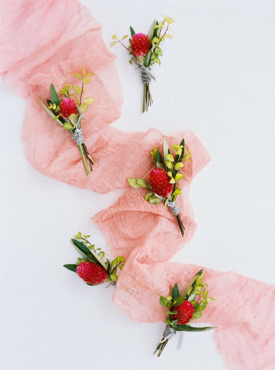 Floral boutonnieres on a delicate pink fabric runner