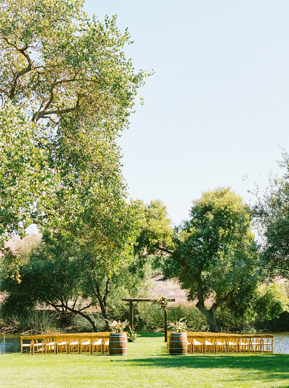 Outdoor wedding ceremony with wooden chairs and arbor