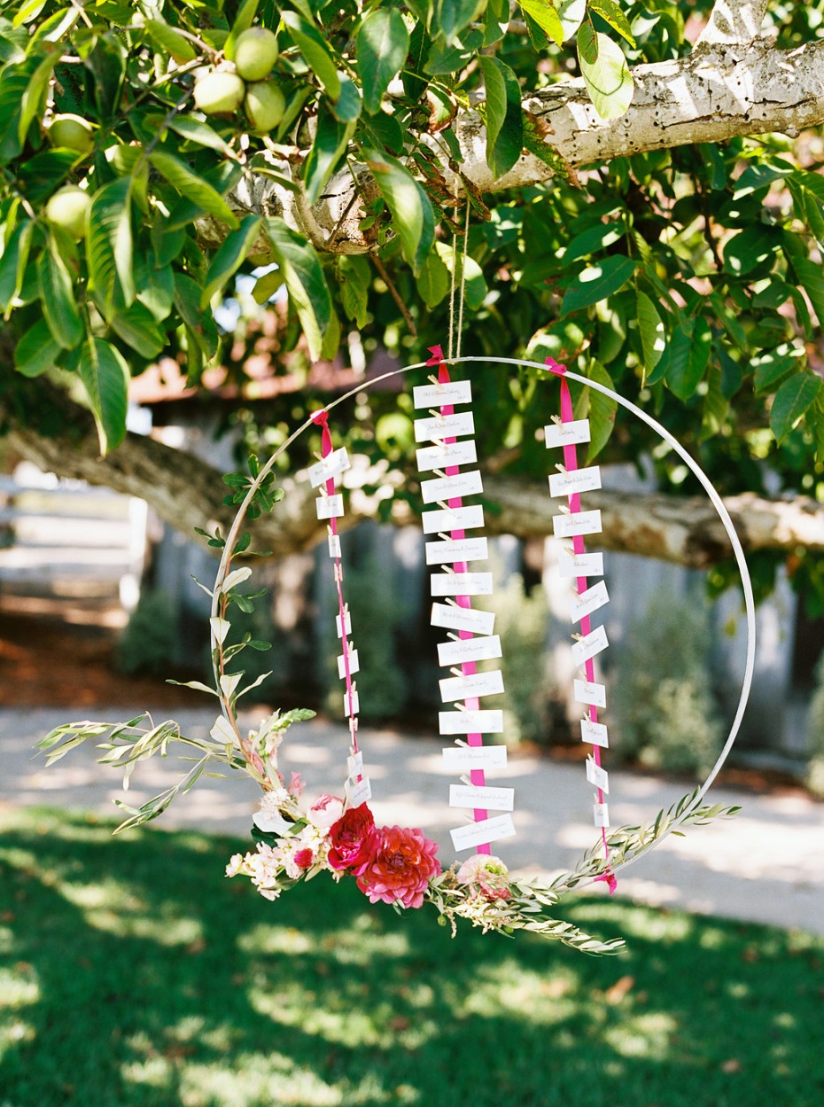 Elegant wedding seating chart hung from a tree branch