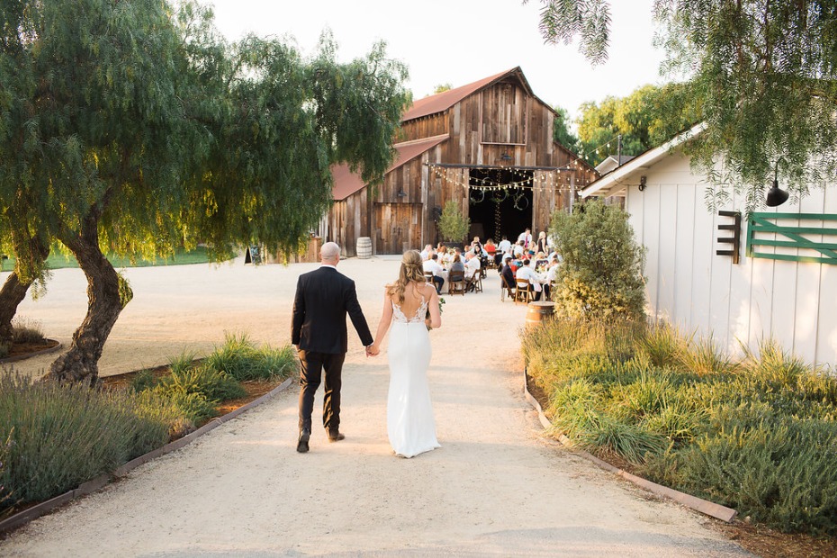 Bride and groom walking to rustic barn wedding reception