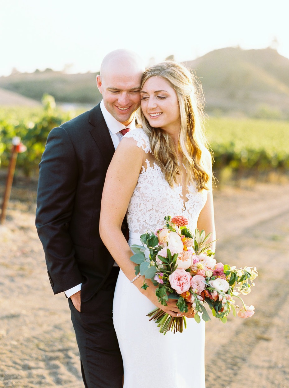 Happy newlywed couple embracing in vineyard wedding attire