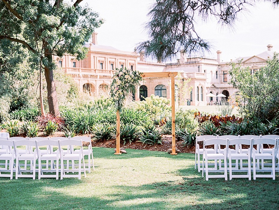 Wedding venue with white chairs and archway in front of mansion