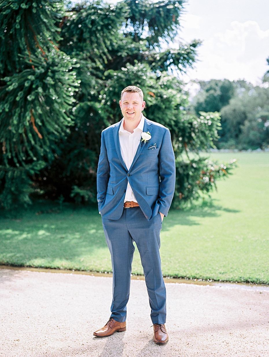 Smiling groom in a blue suit standing for a wedding portrait photo