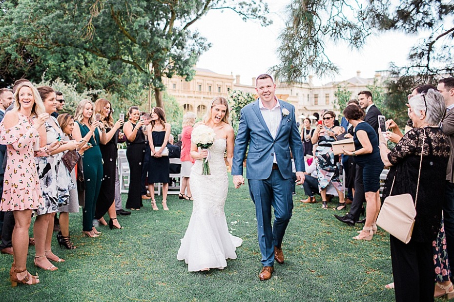 Newlyweds exit wedding ceremony held outdoors on green grass