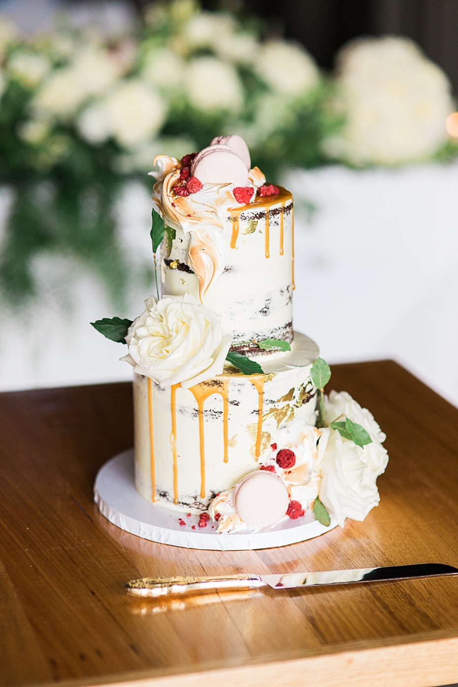 Elegant two-tier wedding cake with caramel drips and floral accents