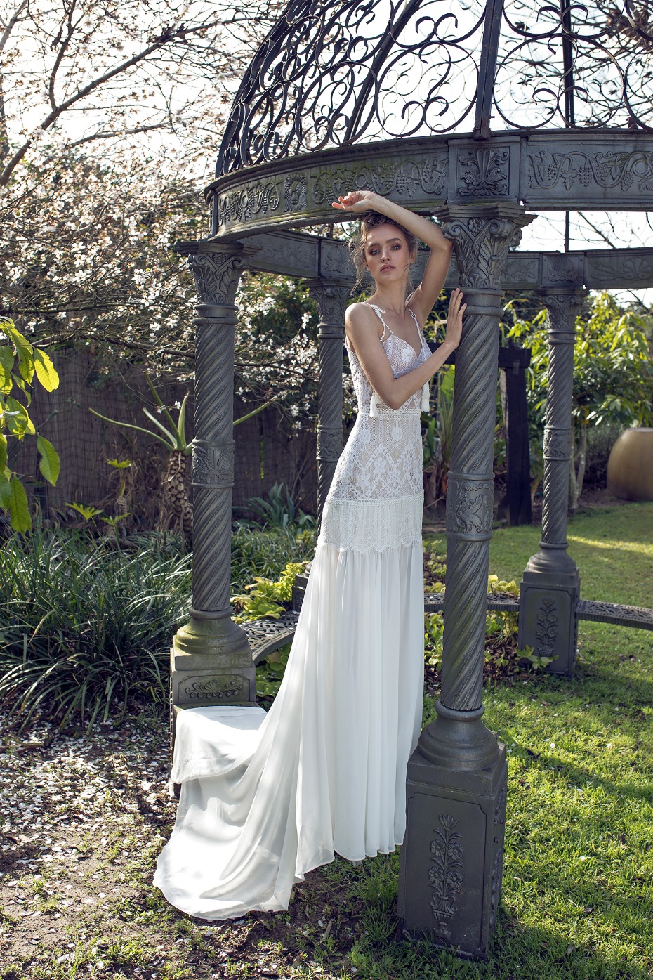 Elegant bride in white dress posing outdoors under a gazebo