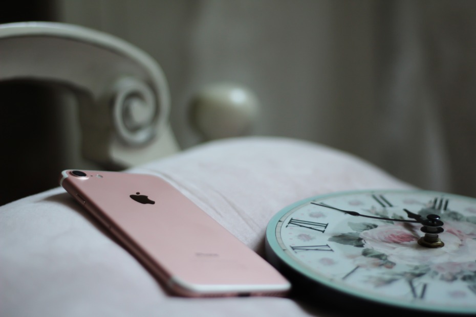 Rose gold iPhone and vintage clock on a plush cushion