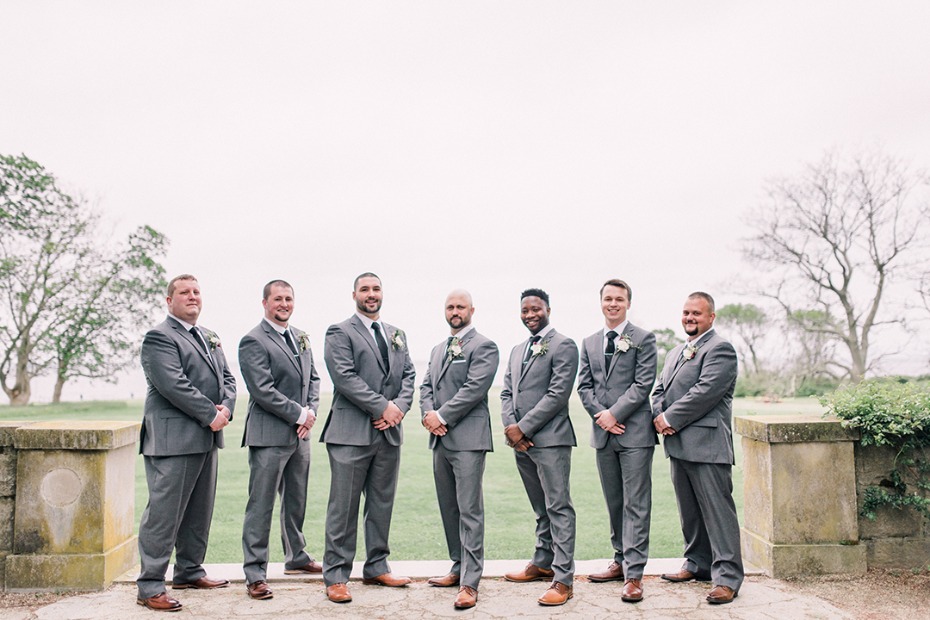 Groomsmen in stylish grey suits posing outdoors for a wedding photo