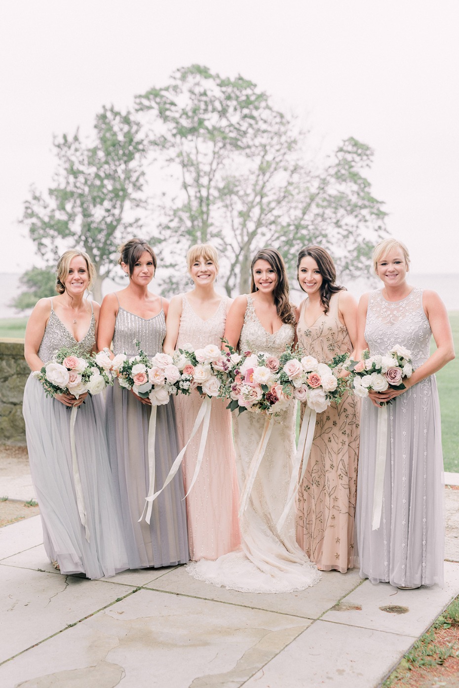 Bridesmaids in long gowns holding bouquets of flowers