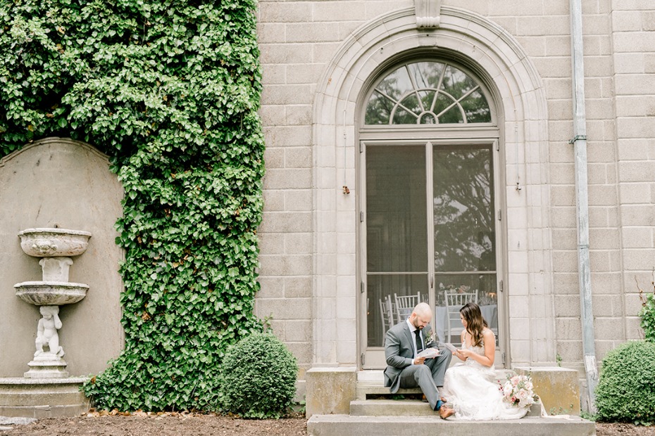 Bride and groom reading vows outside ivy covered estate