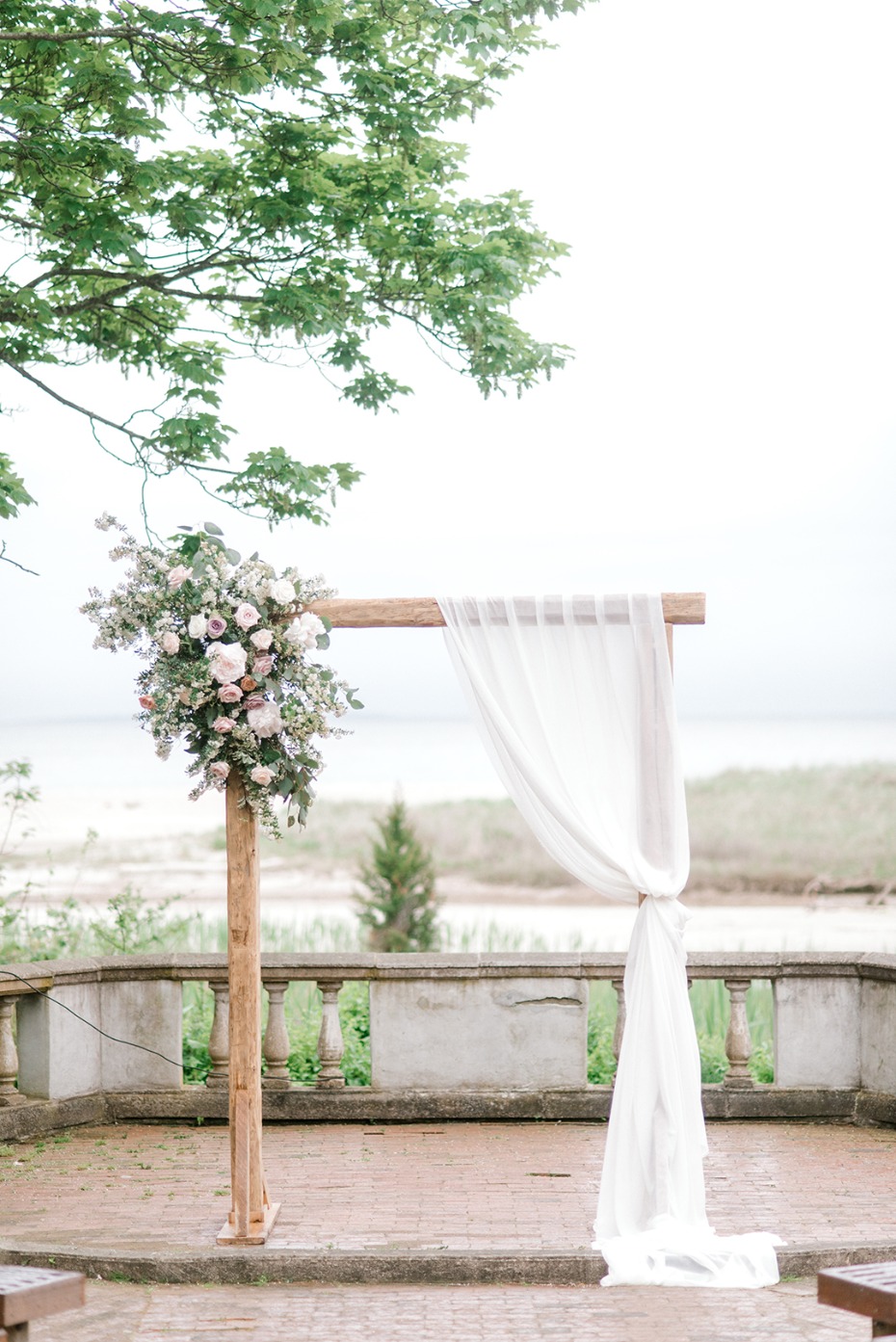 Wedding arch with flowers and draped fabric in front of the sea