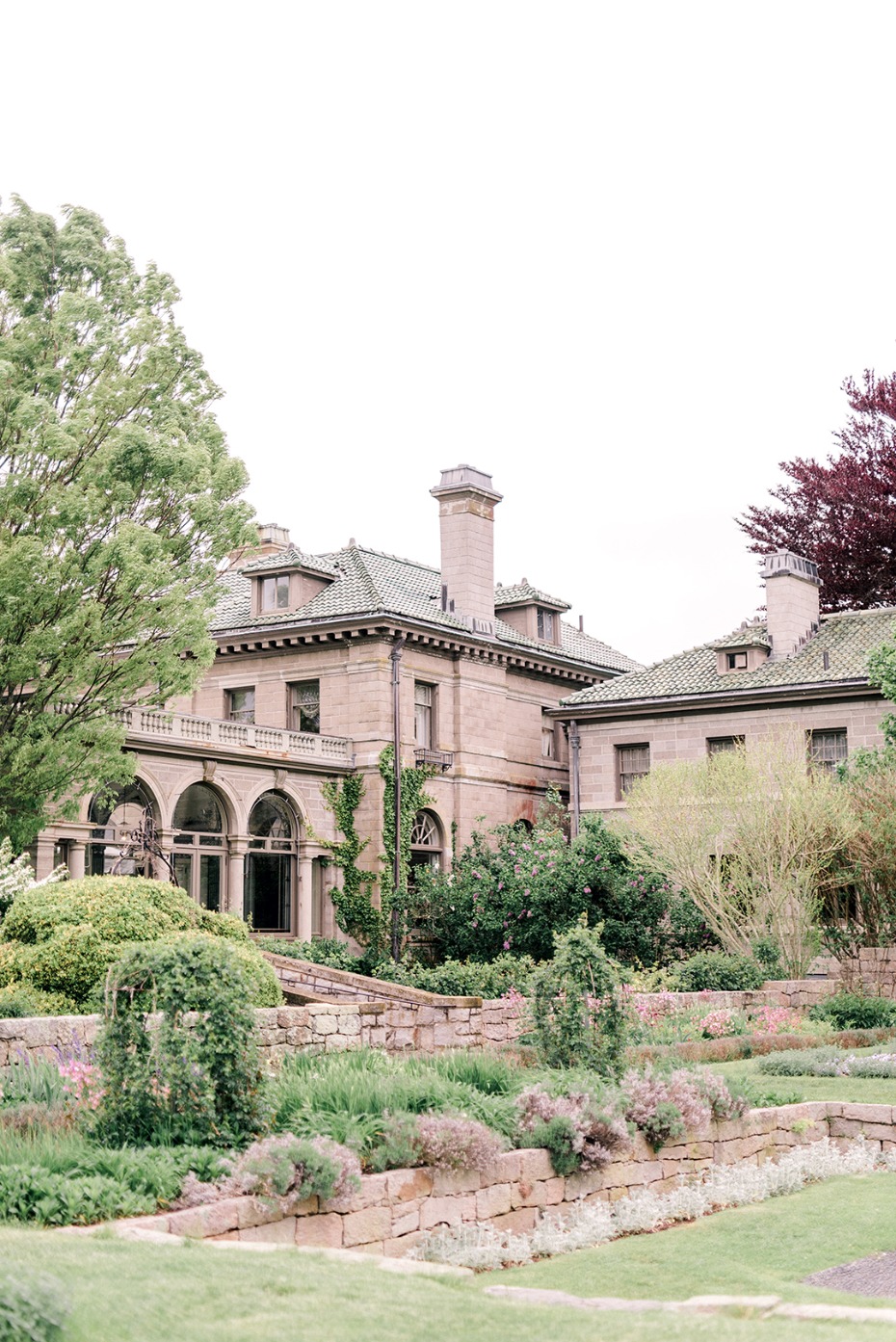 Large historic house surrounded by lush gardens and trees