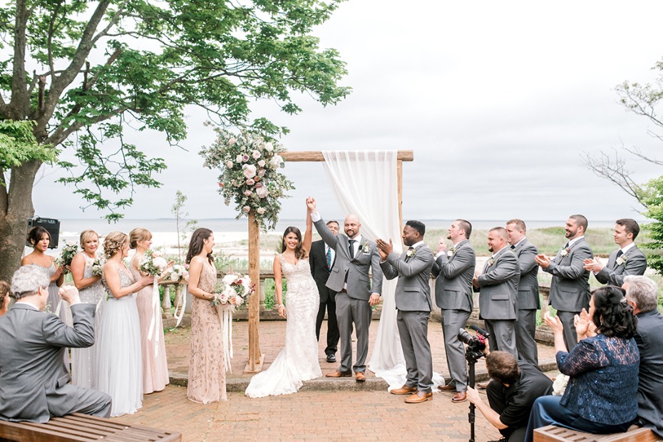 Newlyweds celebrate their wedding vows with joy and cheers near the sea