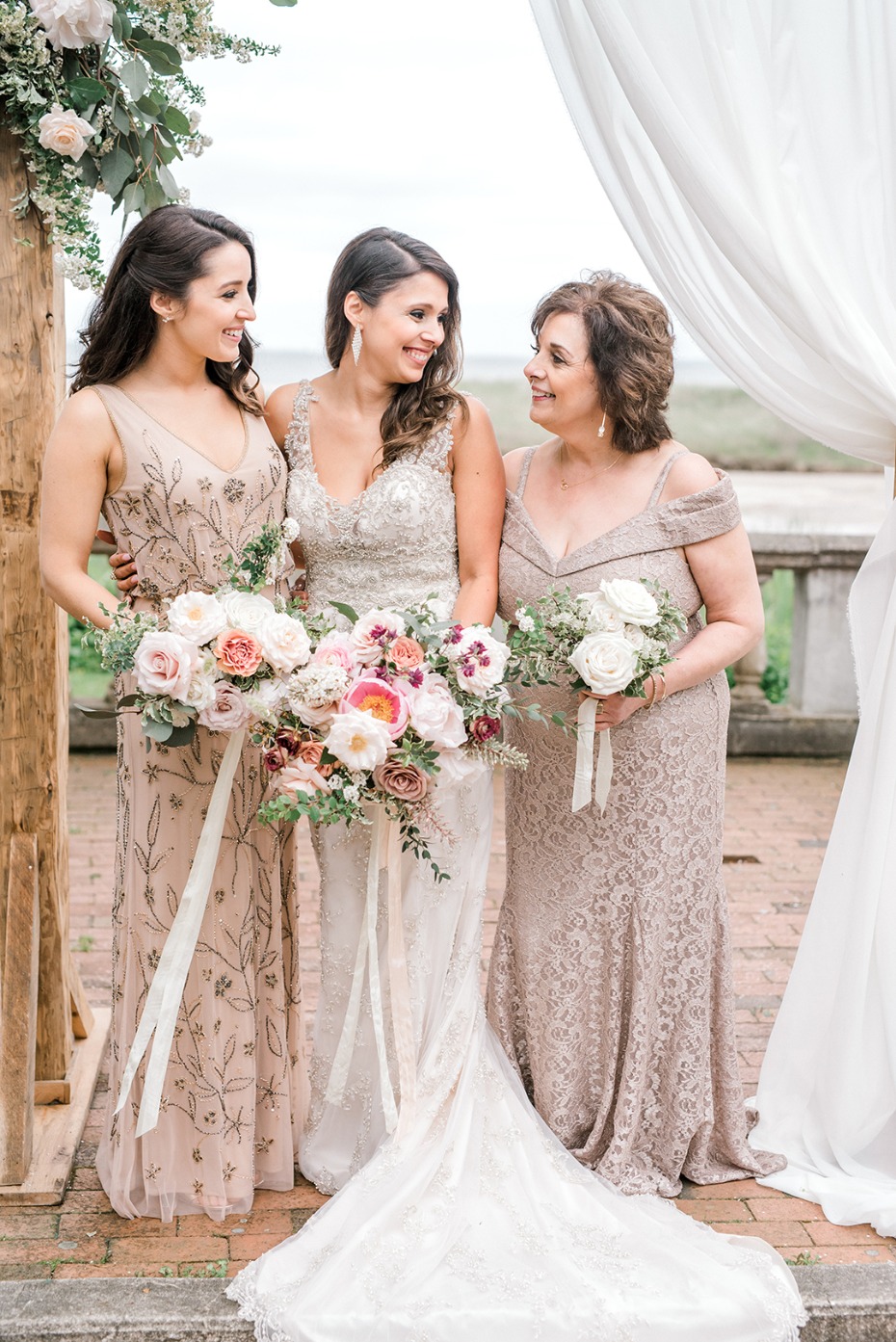 Three women smiling with bouquets, wedding photo