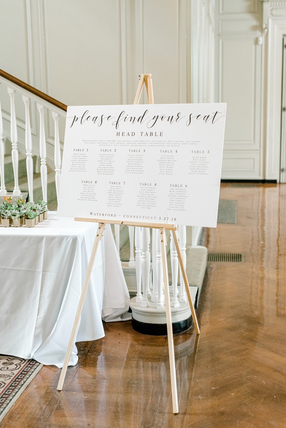 Elegant wedding seating chart on a wooden easel in a bright hall