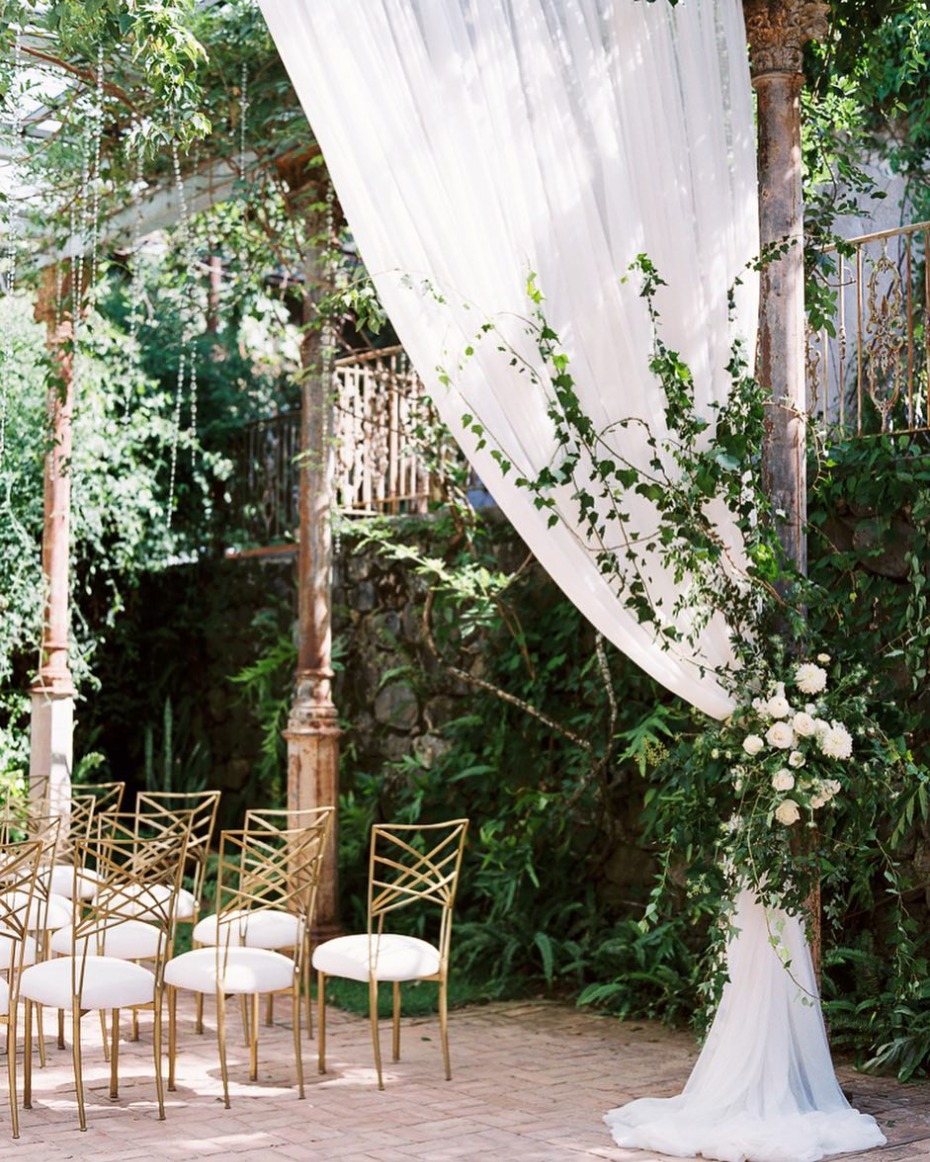 Outdoor wedding setup with draped fabric and greenery