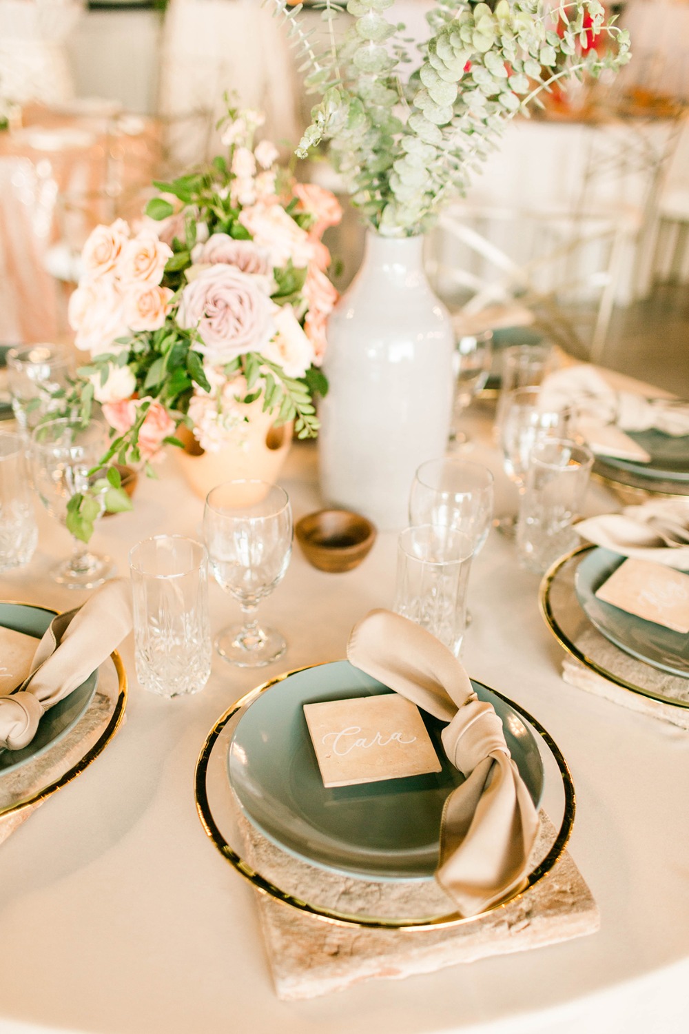 neutral and teal wedding place setting with tile chargers and place cards
