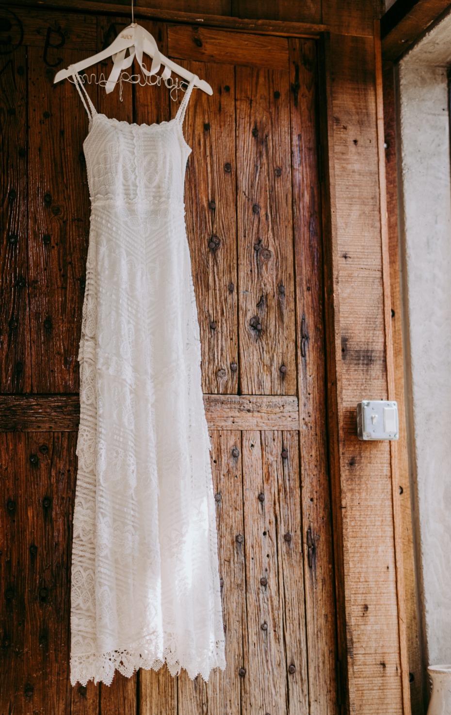 Elegant white lace wedding dress hanging on a wooden door
