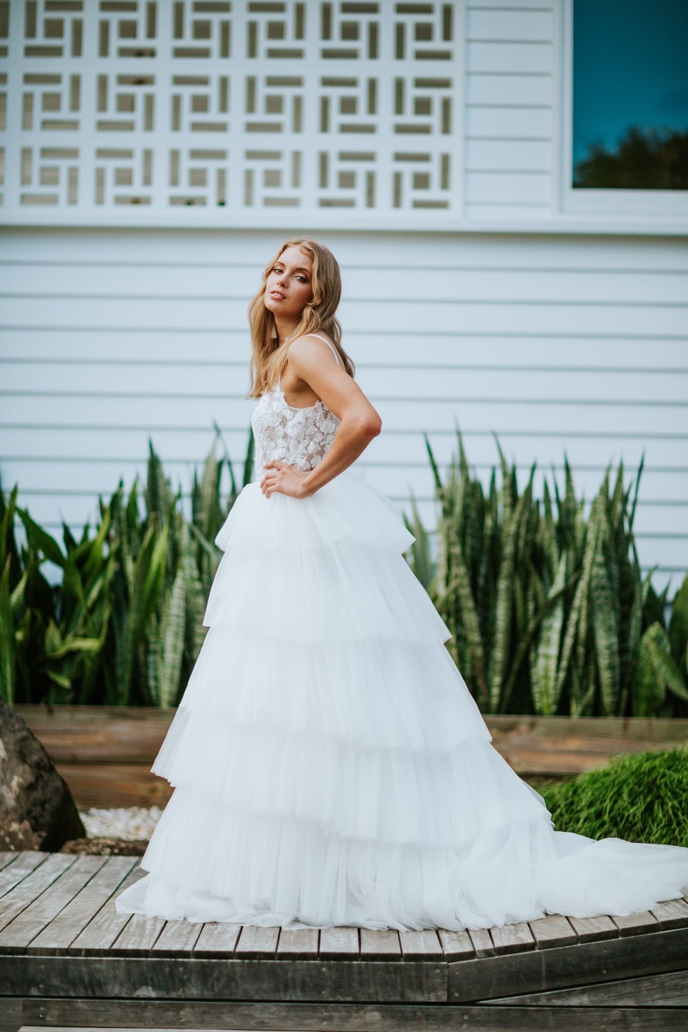 Blonde bride poses in tiered tulle wedding gown outdoors
