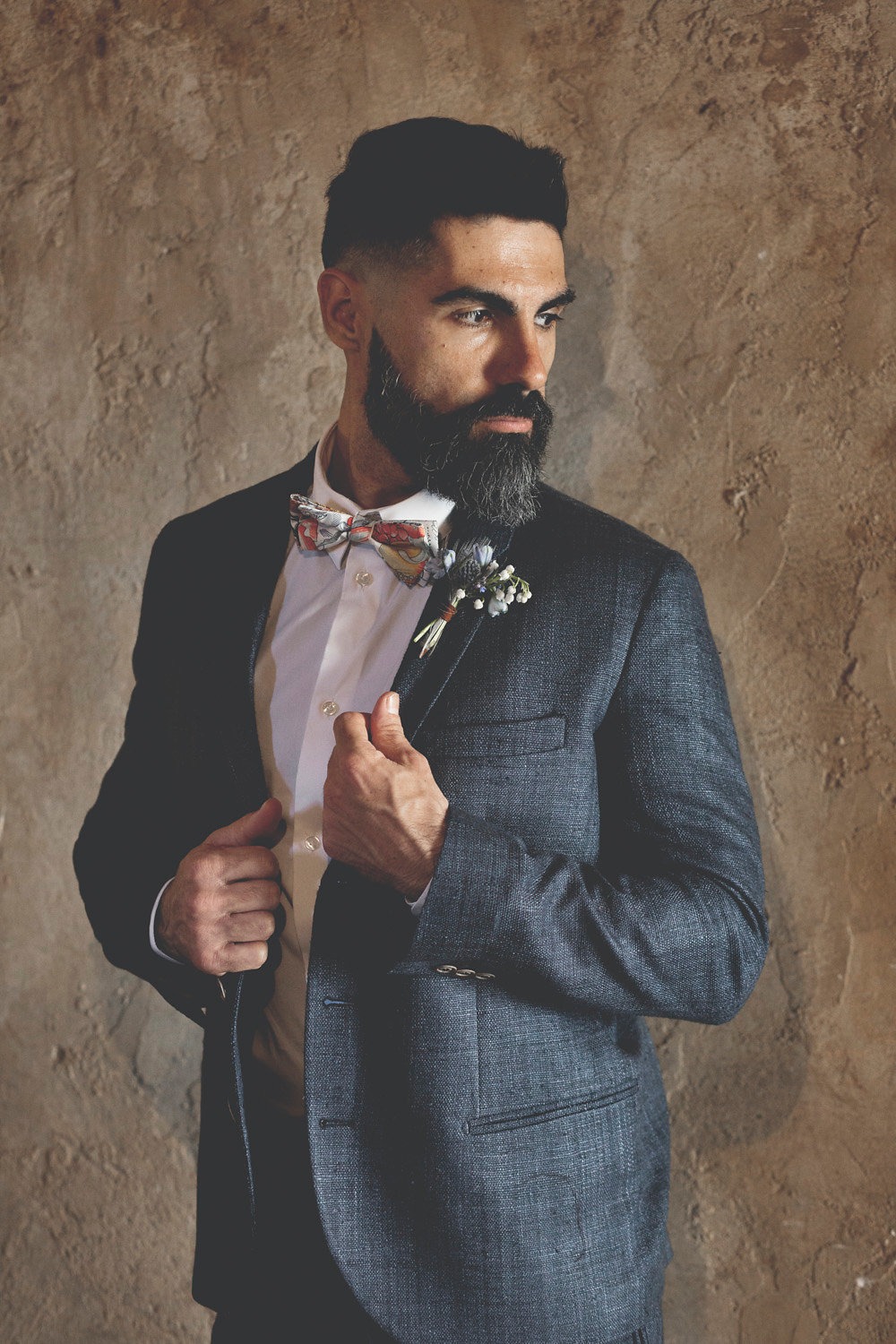 groom in navy suit and floral bow tie