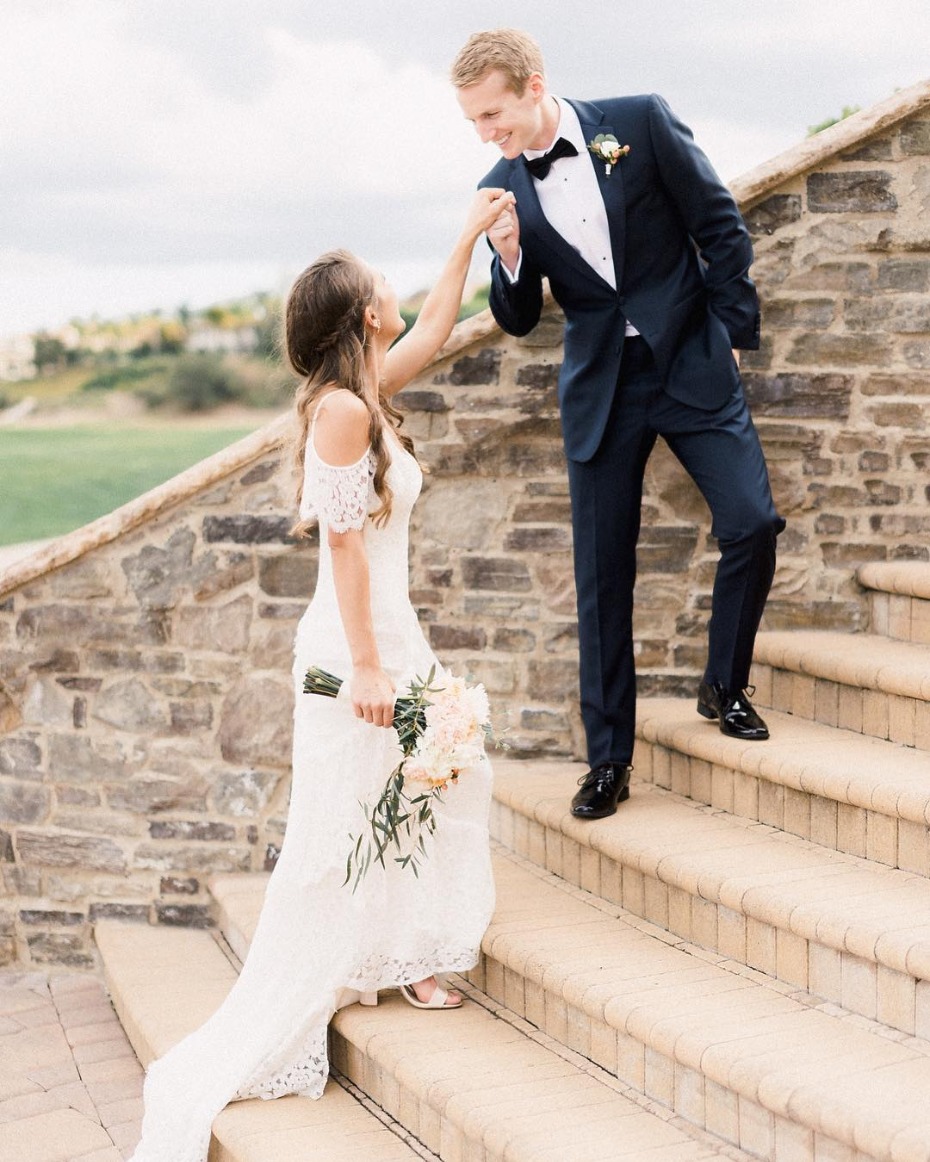 Groom kissing bride's hand while ascending stairs