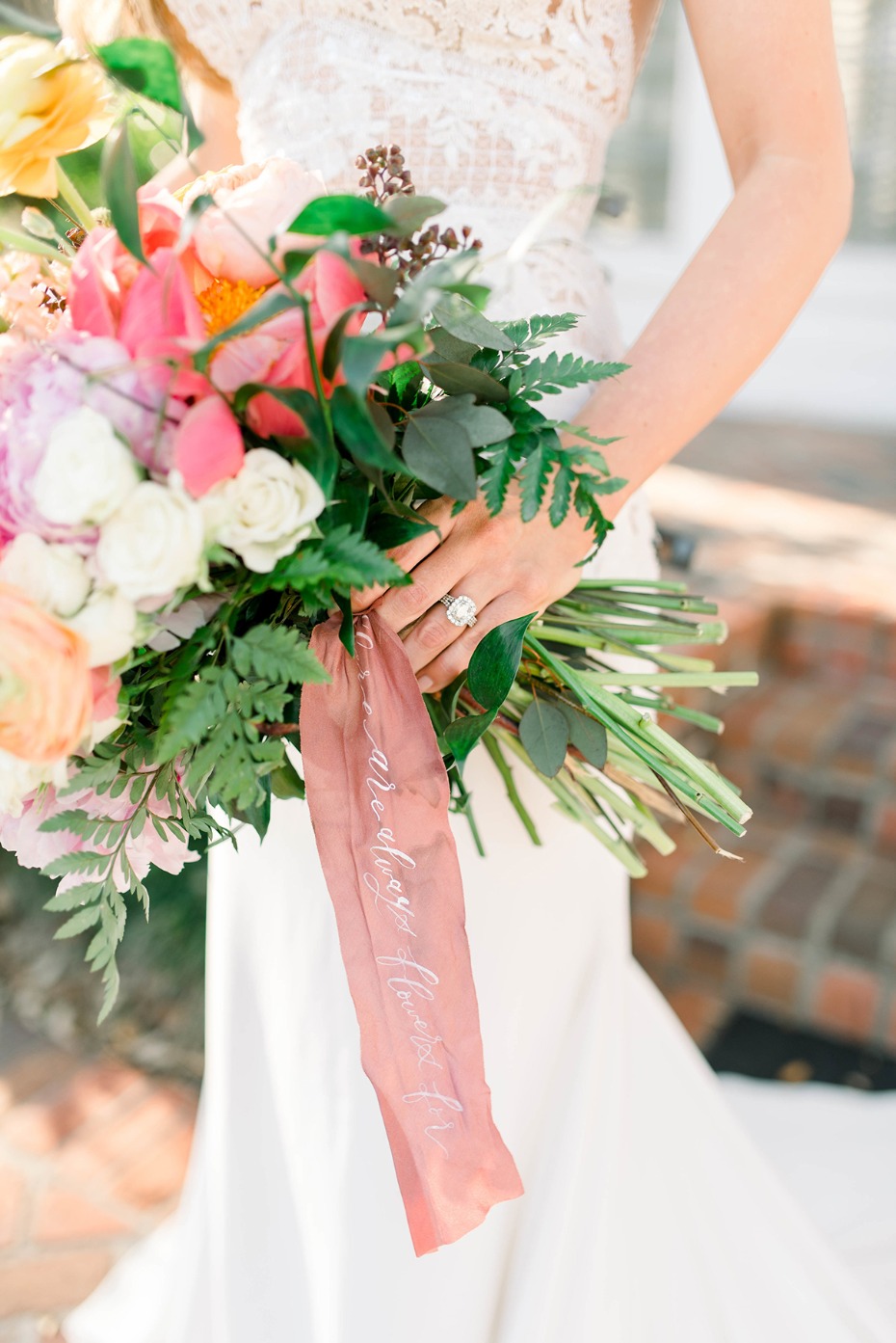 Bride holds vibrant floral bouquet with inscribed ribbon