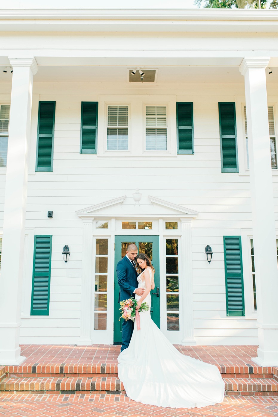 Bride and groom portrait in front of white house facade