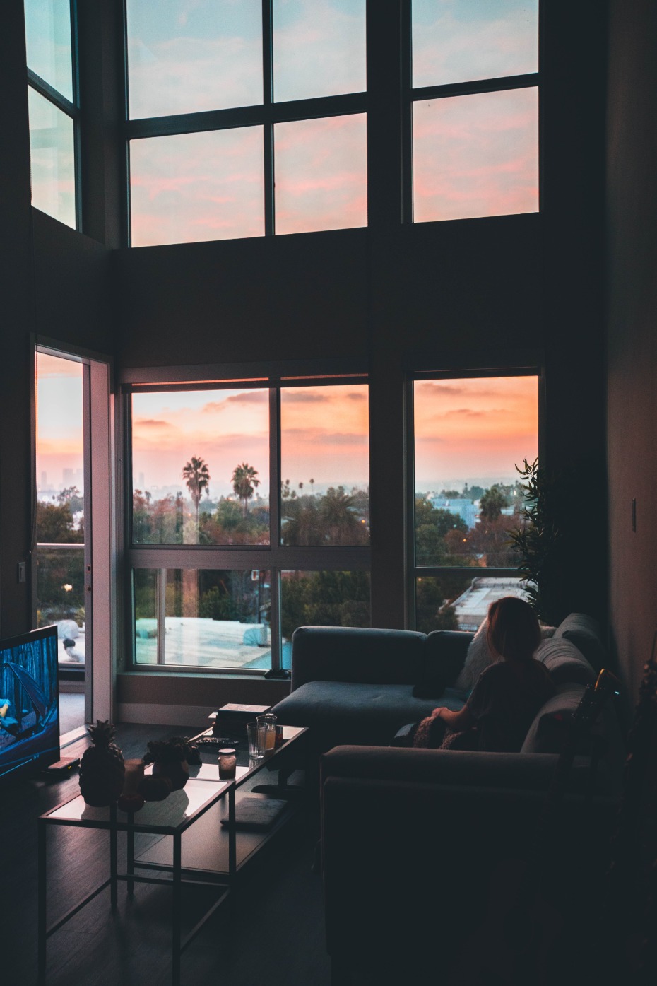 Woman watching tv with sun setting outside