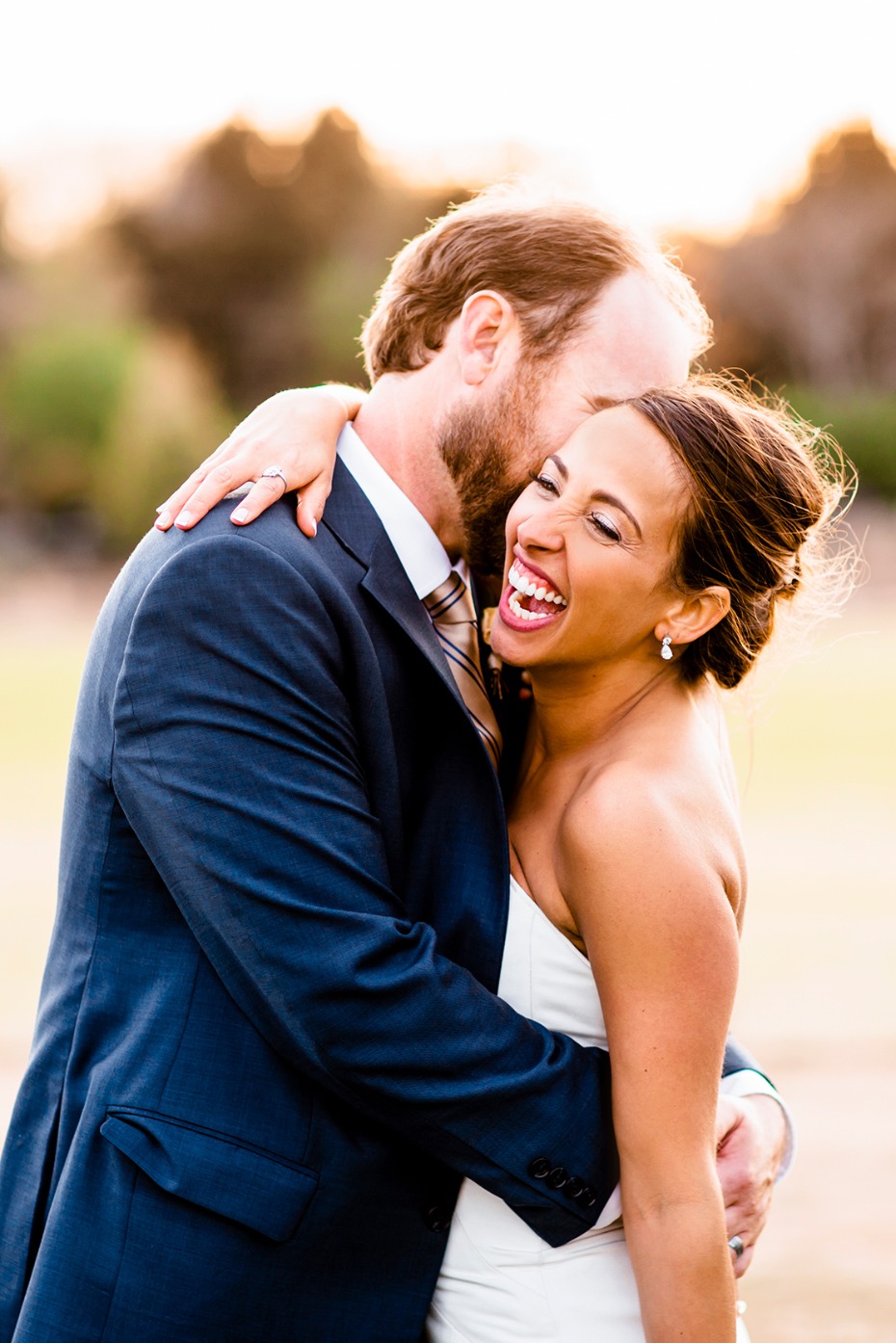 Bride laughing joyfully in grooms loving embrace wedding day