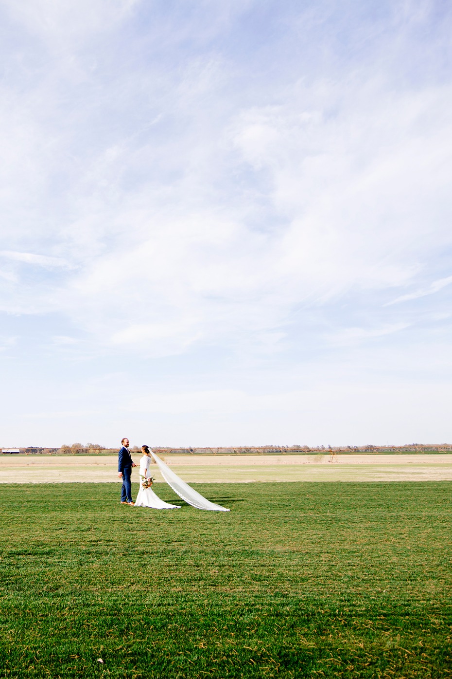 Bride and groom on a field celebrate their wedding day in the sun