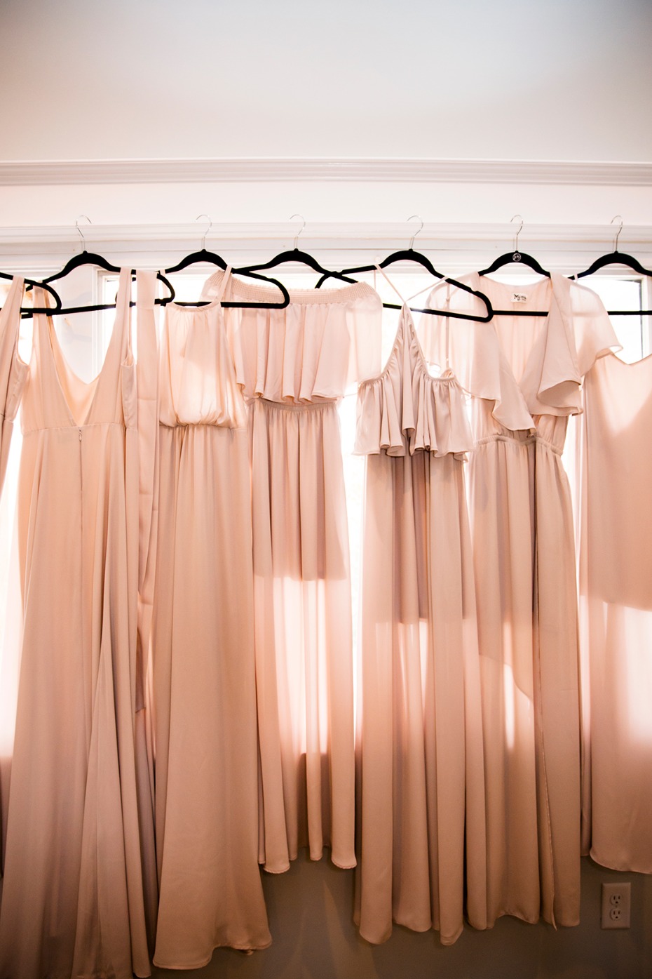 Bridesmaids dresses in soft pink hanging on hangers