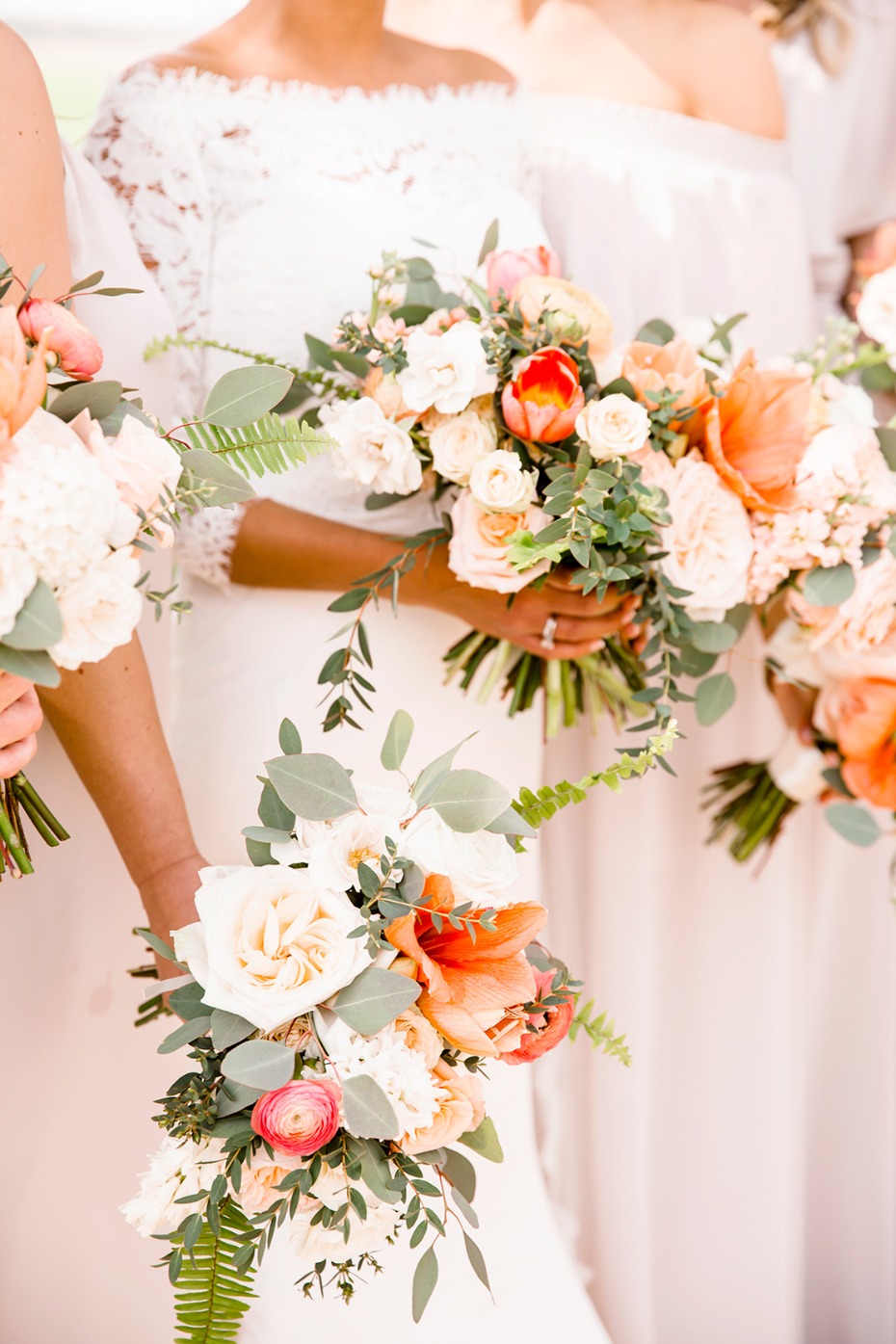 Bridesmaids holding beautiful peach and white floral bouquets for wedding