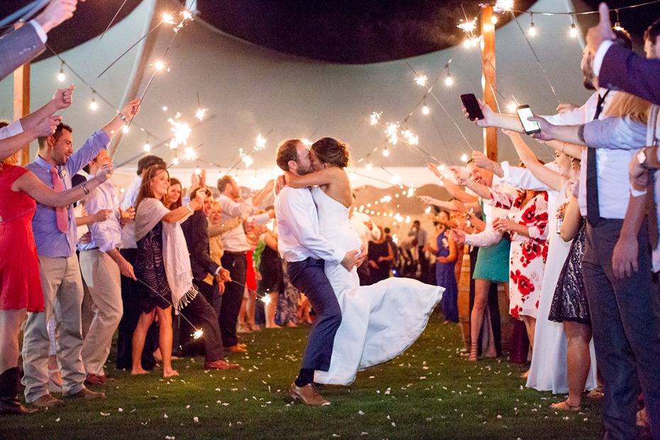 Bride and groom kiss surrounded by sparklers at wedding
