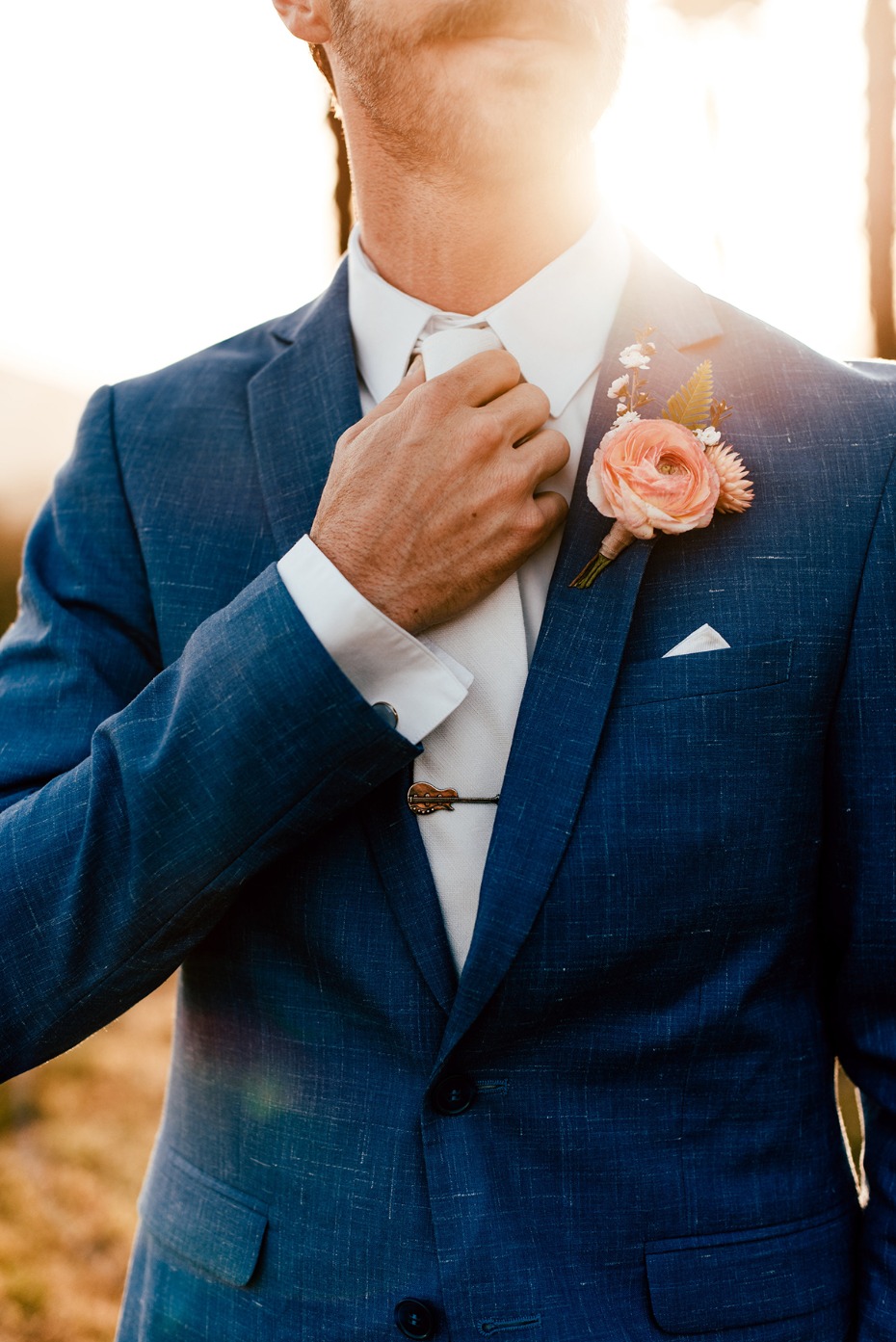 groom in blue suit with guitar tie clip