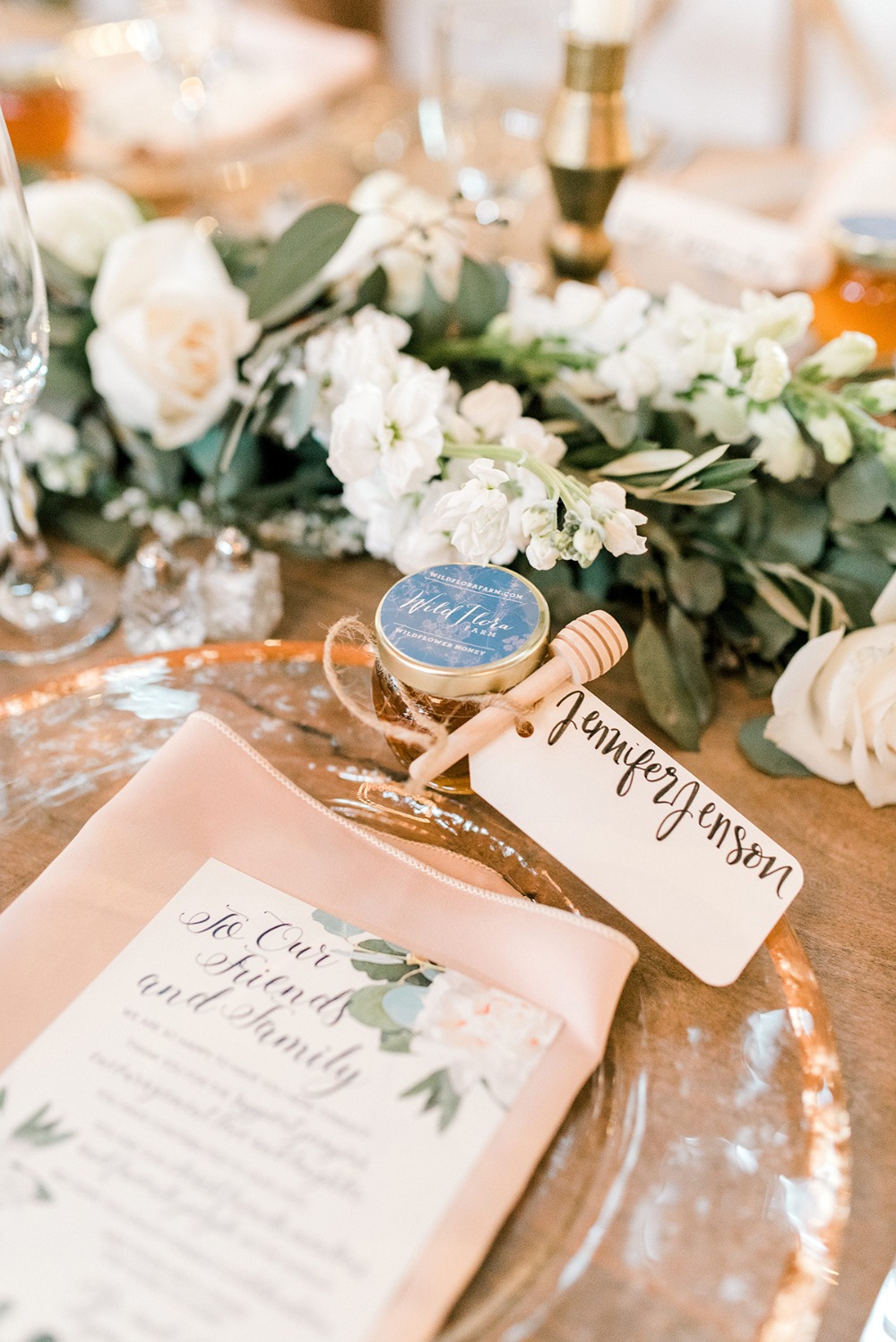 Wedding table setting with flowers, honey favors, and place setting