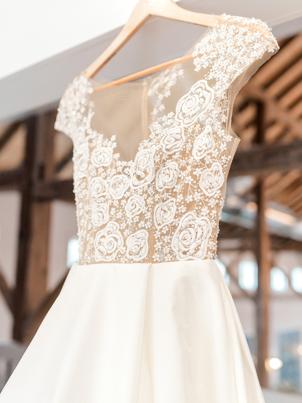 Elegant white wedding dress with floral bodice on a hanger
