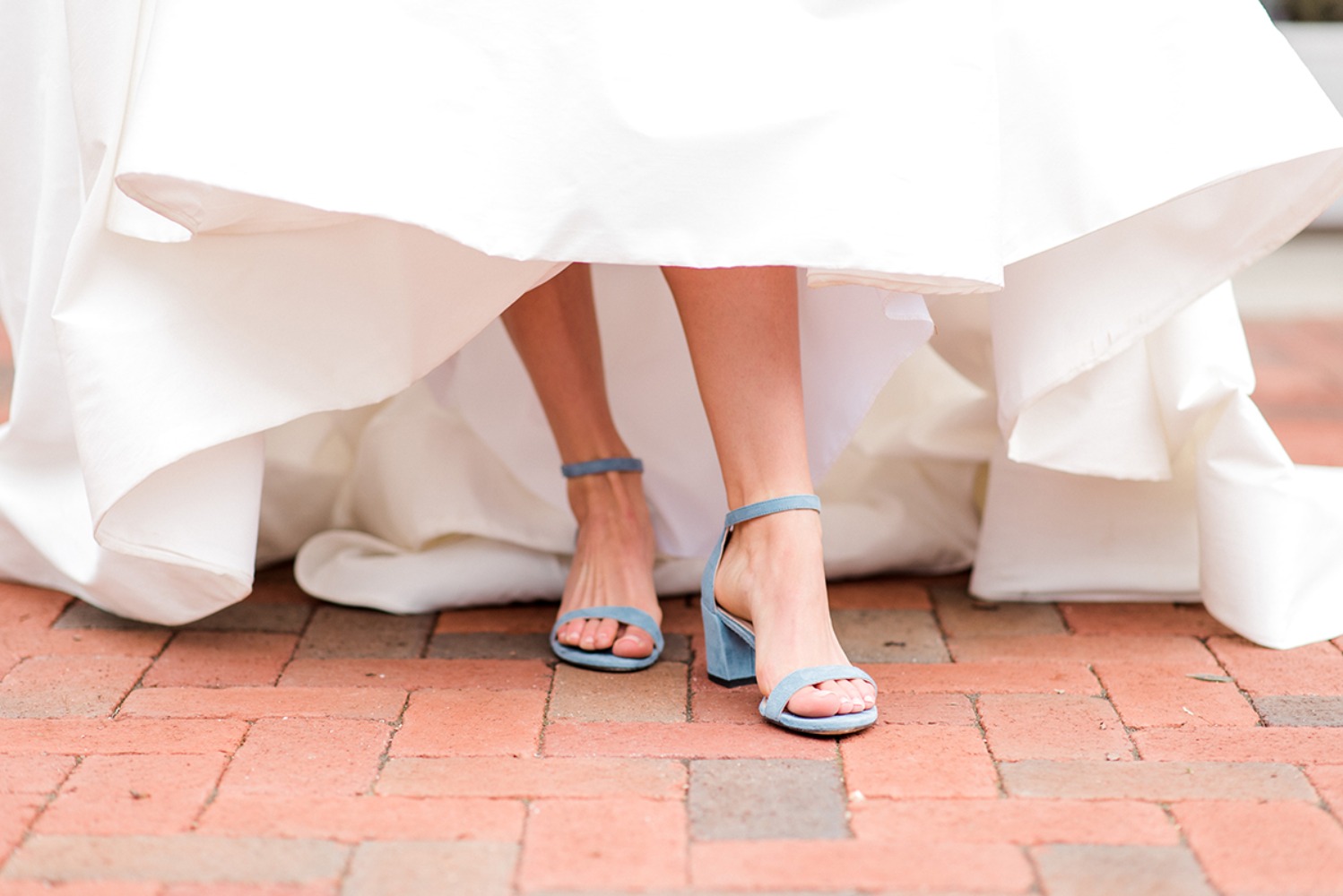 Bride's legs and stylish blue heels under the wedding dress
