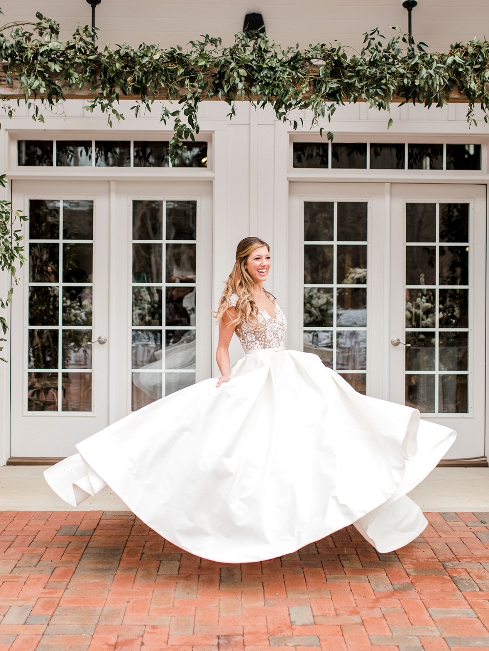 Bride twirling in a white wedding dress in front of doors