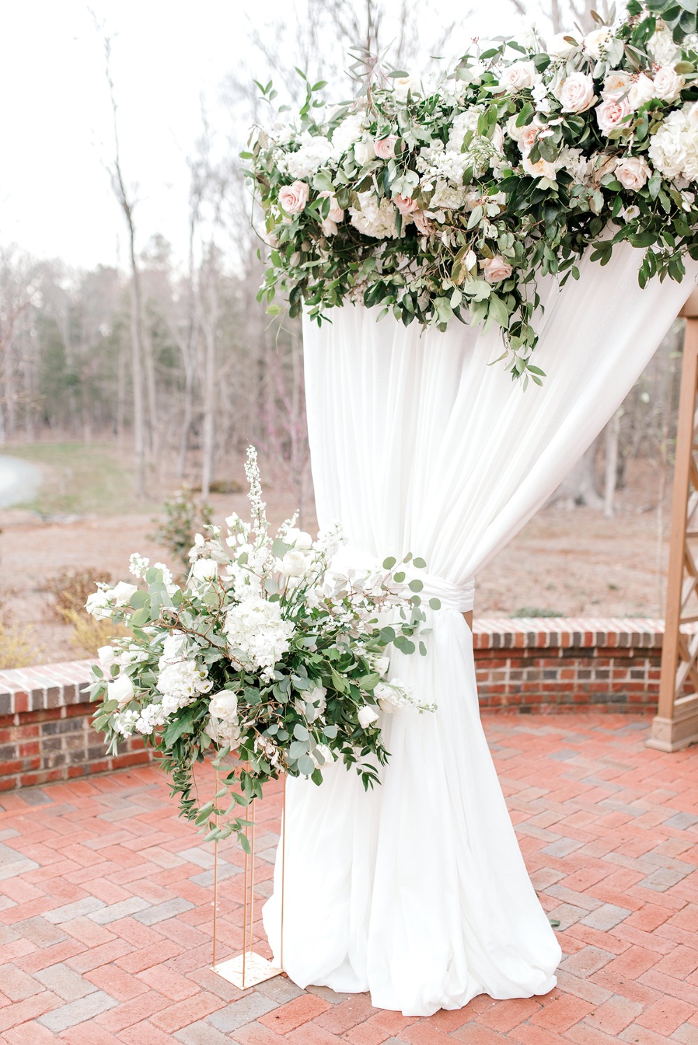 Elegant outdoor wedding altar decorated with white flowers and fabric
