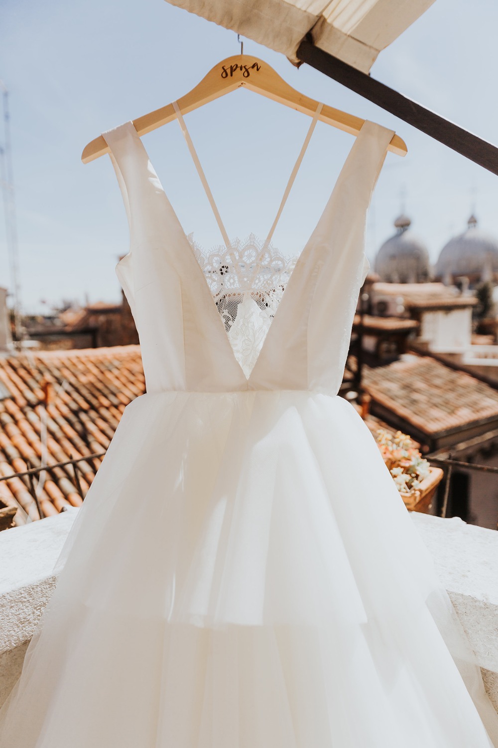 Elegant white wedding dress hanging on a wooden hanger, ready to wear