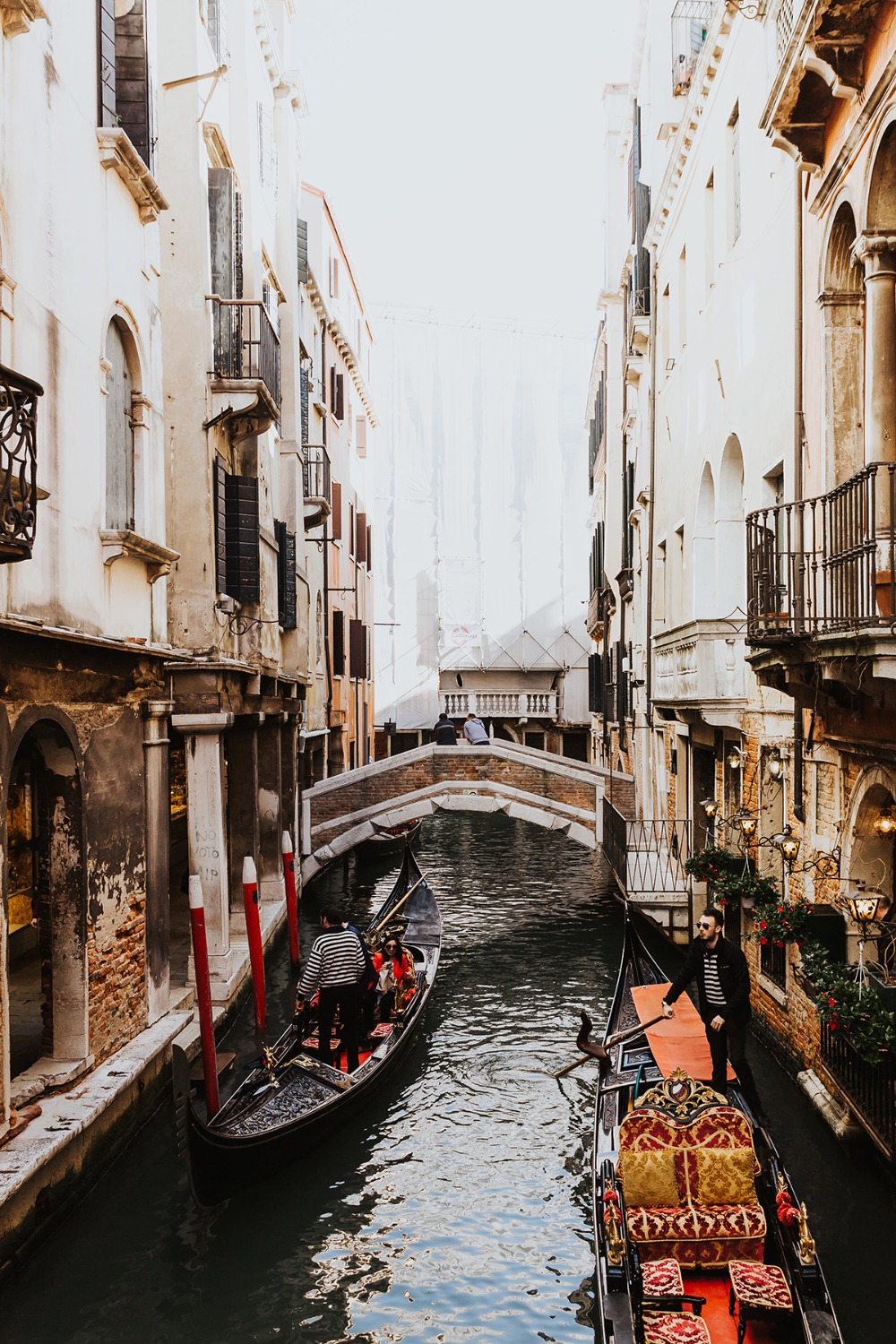 Gondolas in a canal beneath a bridge in Venice, Italy