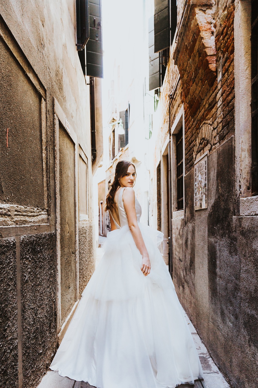 Bride in a stunning wedding dress in a narrow Italian alleyway